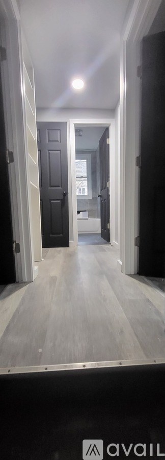 A long hallway with a door on the left and a mirror on the right.
