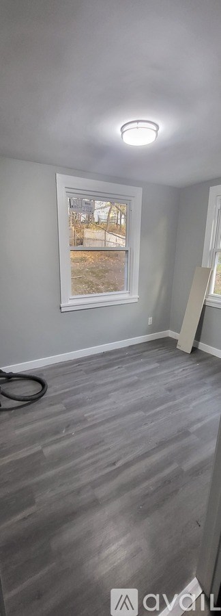 A room with a grey floor and a window showing an outdoor view.