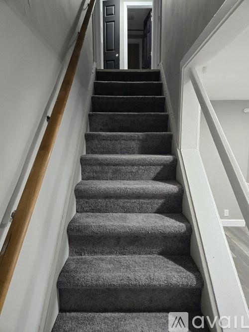 A staircase with a grey carpeted runner and wooden handrails.