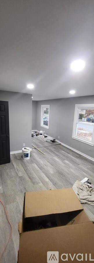 A room with grey walls and a grey floor with a cardboard box on it.