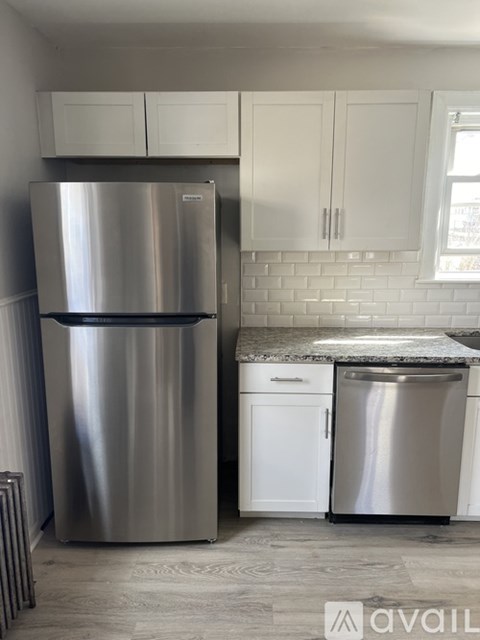A stainless steel refrigerator stands next to a white dishwasher in a kitchen.