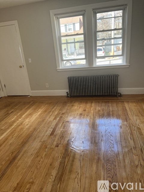 A room with wooden floors and a window with a view of the street outside.