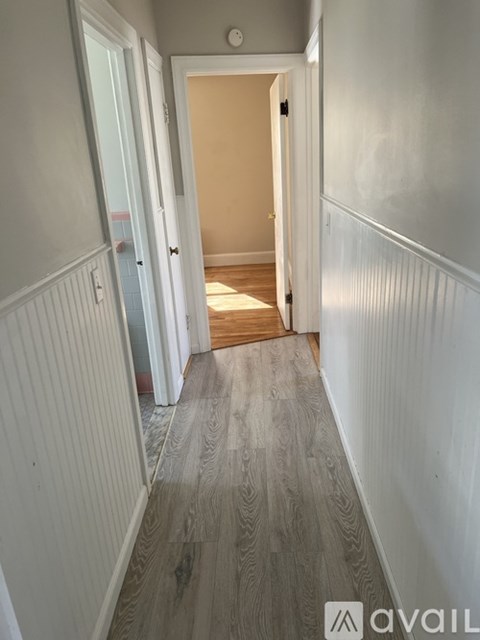 A long hallway with wood flooring and white walls.