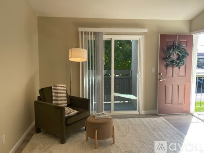 A living room with a chair, a table, and a door with a wreath on it.
