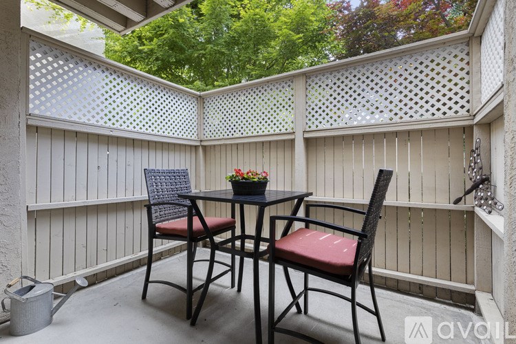 A patio with a table and chairs and a lattice fence.