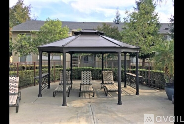 A gazebo with four chairs and a table is surrounded by a fence.