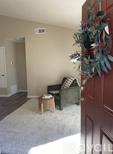 A room with a couch, a chair, and a wreath on the door.