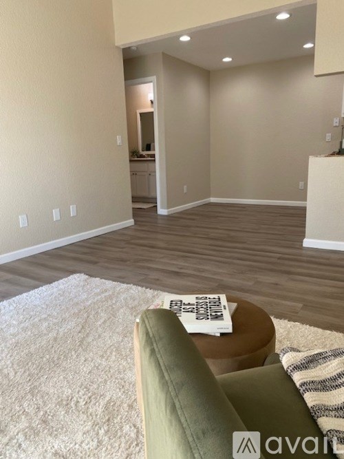 A living room with a green couch and a white rug.