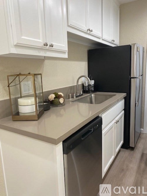 A kitchen with white cabinets and a black refrigerator.