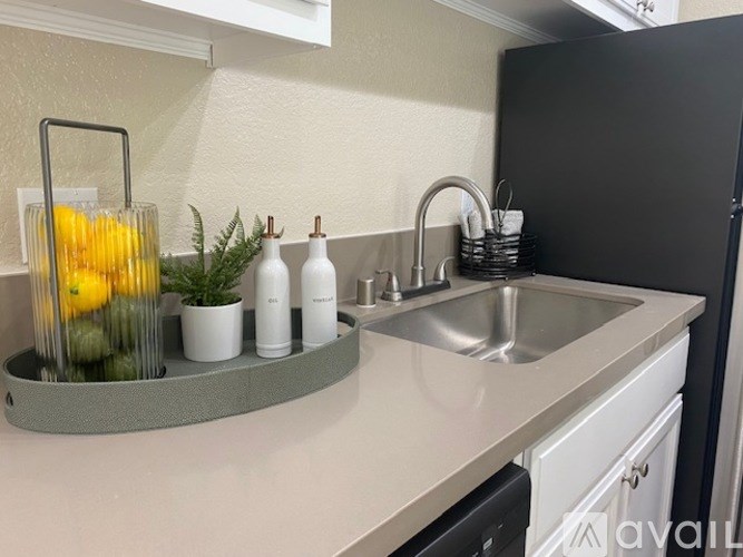 A kitchen counter with a sink, a vase with yellow flowers, and some greenery.