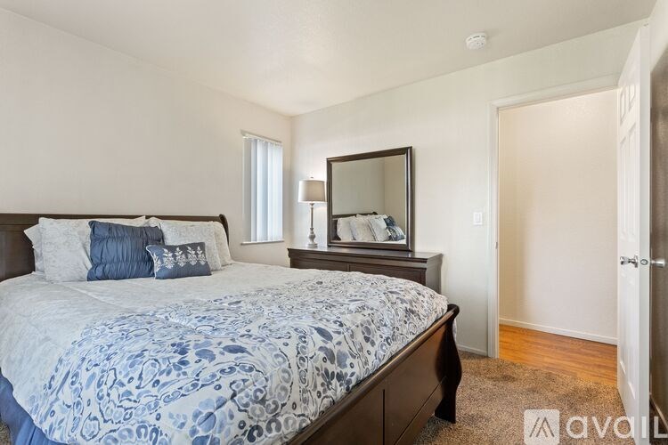 A bedroom with a large bed and a mirror on the dresser.
