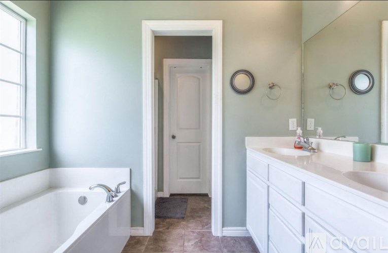 A white bathroom with a tub, sink, and mirror.
