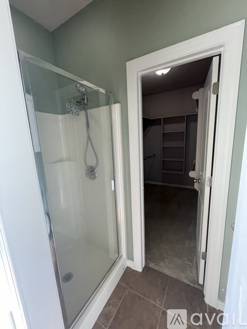 A bathroom with a glass shower door and a white door.