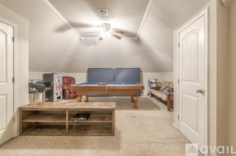 A living room with a pool table and a television.