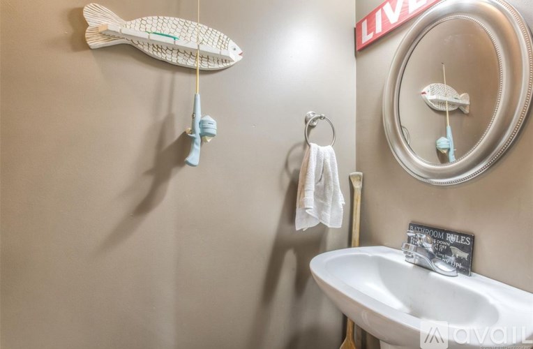 A white fish decoration hangs on a wall above a sink.