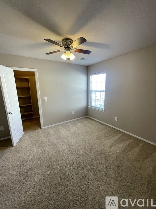A room with a ceiling fan and carpeted floor.