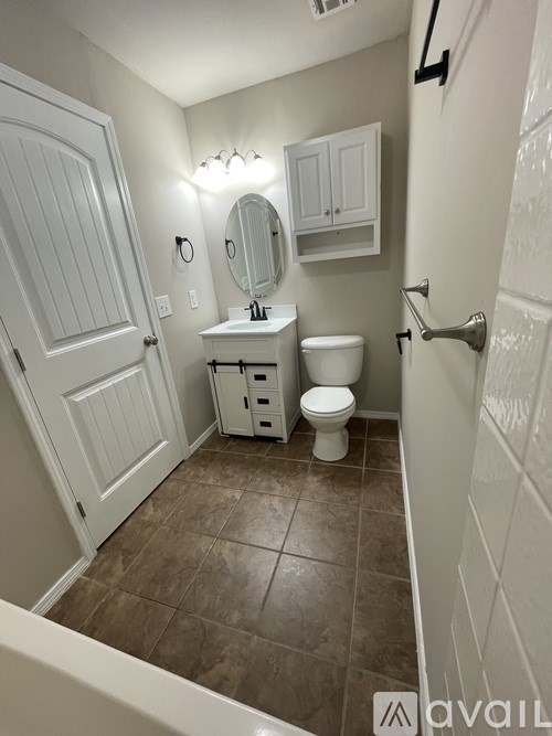 A bathroom with a toilet, sink, and mirror.