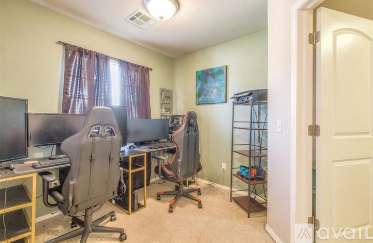 A room with a desk, computer, and chair.