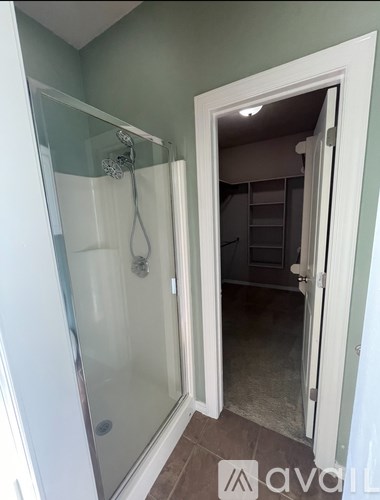 A bathroom with a glass shower door and a white door.