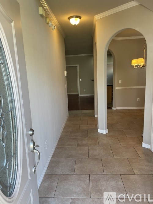 A hallway with a tiled floor and a glass door.