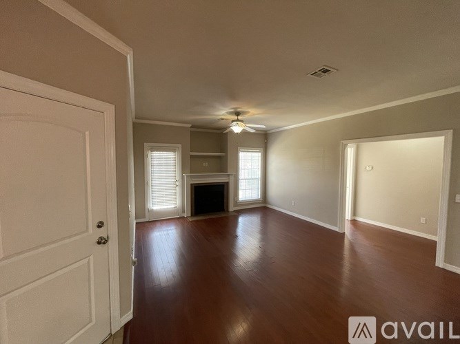 A spacious room with wood flooring and a ceiling fan.