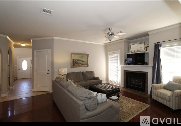 A living room with a grey couch, a fireplace, and a painting on the wall.