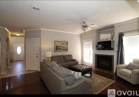 A living room with a grey couch, a fireplace, and a painting on the wall.