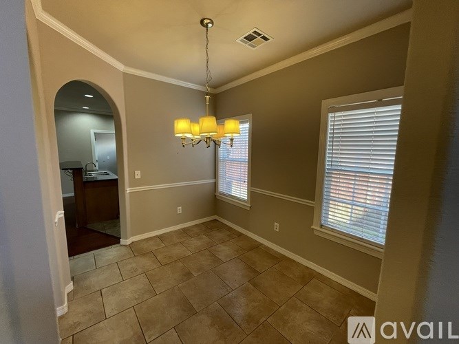 A room with a chandelier, tiled floor, and a window with blinds.
