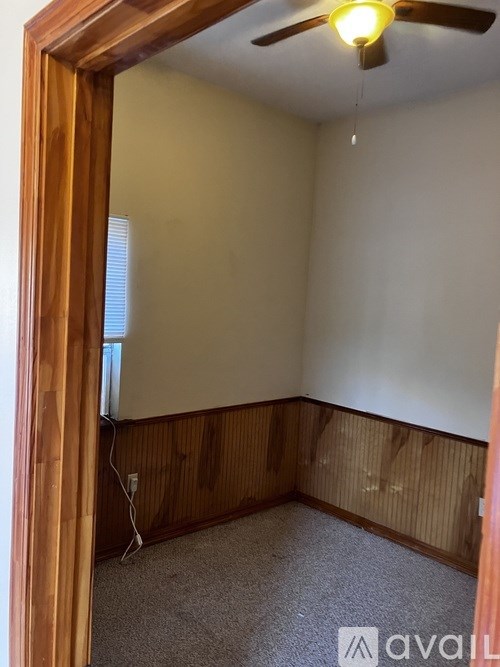 A room with a ceiling fan and a window with blinds.