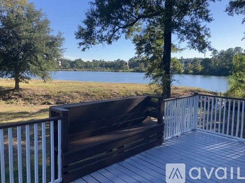 A wooden bench is on a deck overlooking a lake.