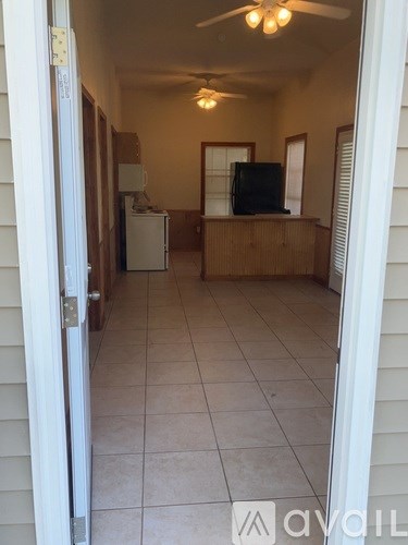 A room with a fan, a television, and a refrigerator.