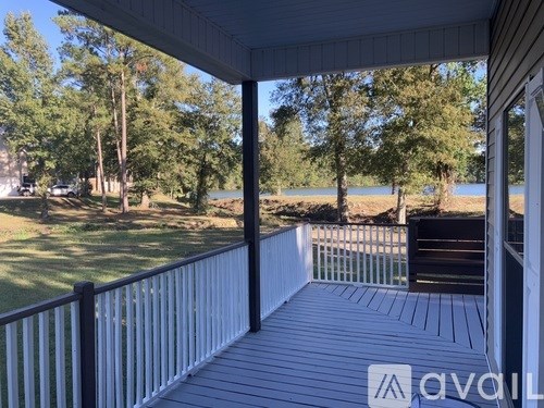A deck with a railing overlooks a grassy area and a body of water.