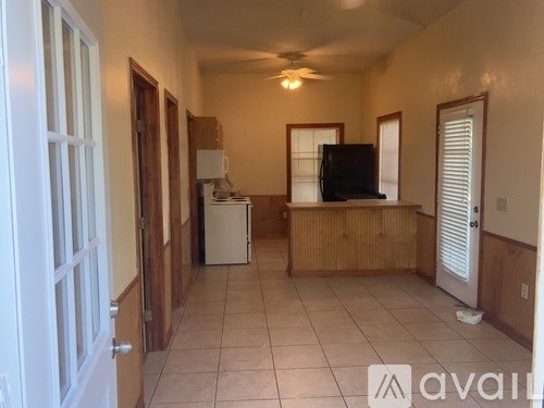 A living room with a television, a refrigerator, and a dining table.
