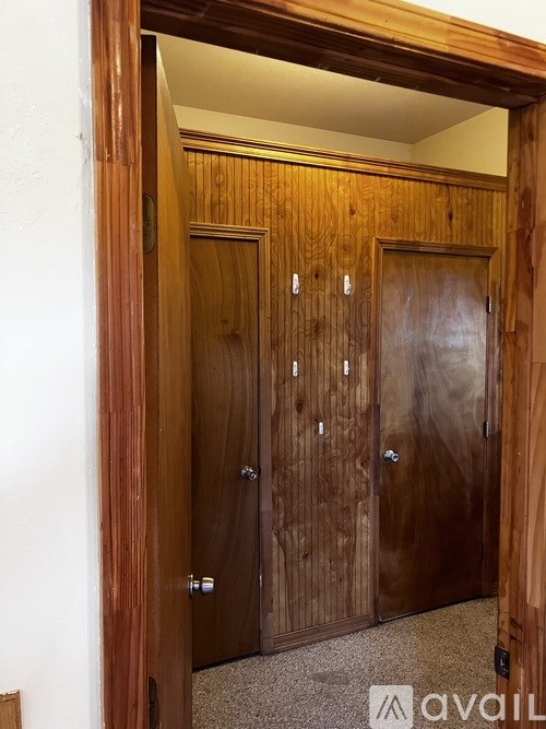 A room with two wooden doors and a white wall.