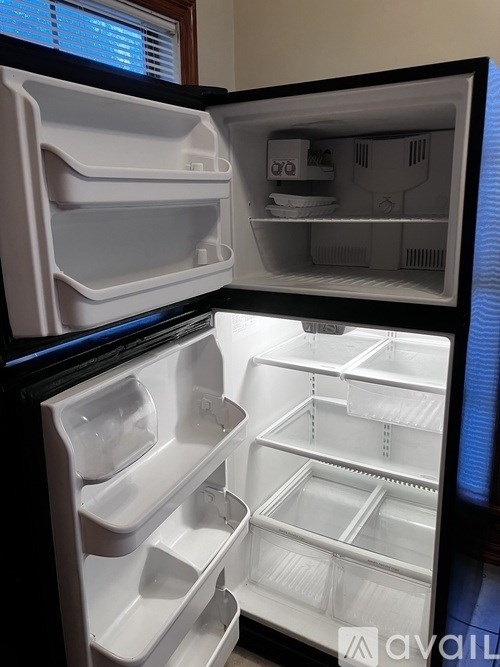 A white refrigerator with its door open showing the empty shelves.