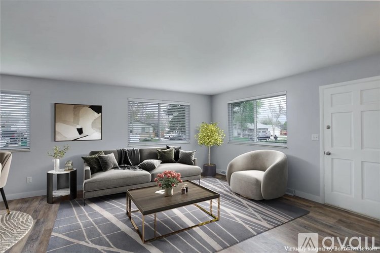 A modern living room with a grey sofa, a coffee table, and a large painting on the wall.
