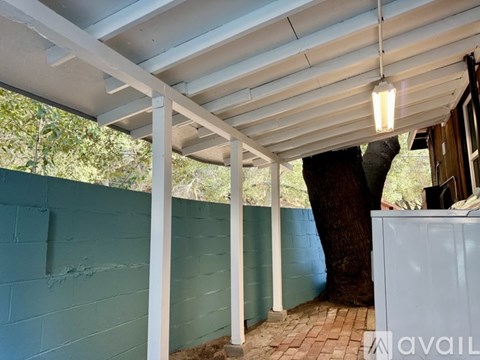 A patio area with a white pergola and a brick floor.