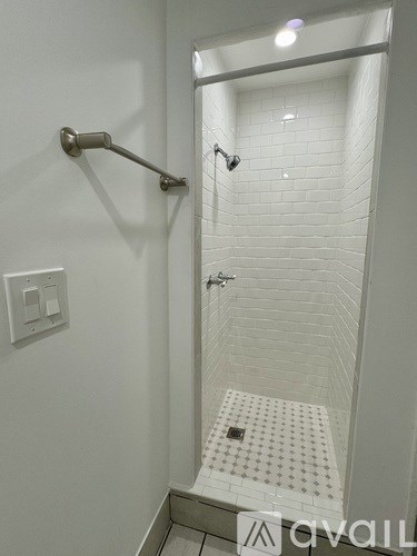 A white tiled shower with a silver shower head and hand held shower.
