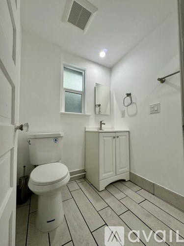A white toilet with a white cabinet and a window above it.