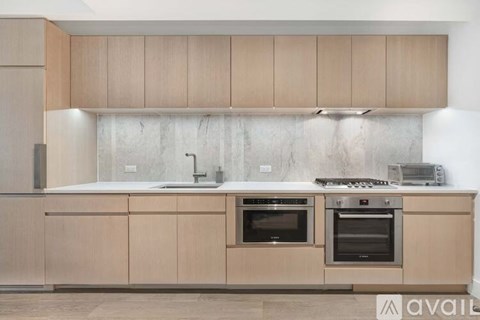 A kitchen with wooden cabinets and a marble backsplash.