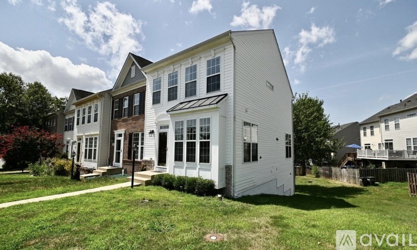 A white house with a black roof is for sale.