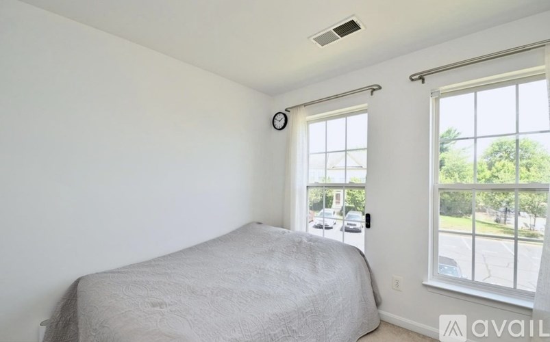 A bedroom with a bed, window, and a clock on the wall.