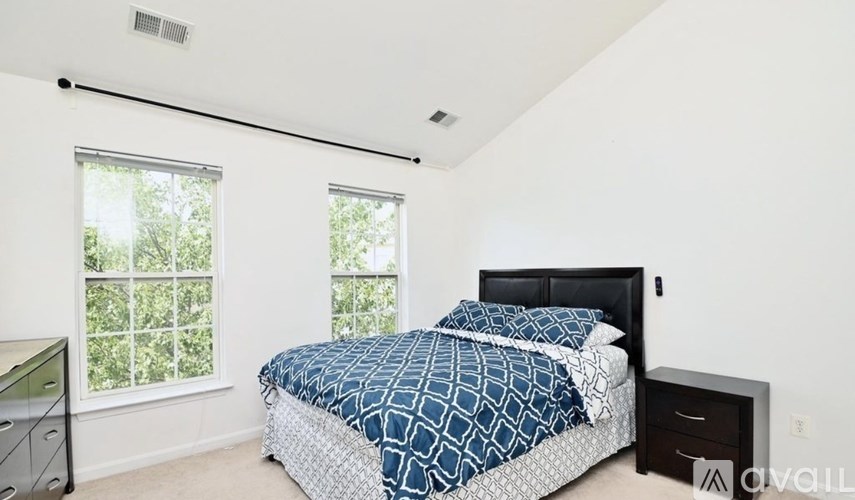 A bedroom with a bed, nightstand, and window.