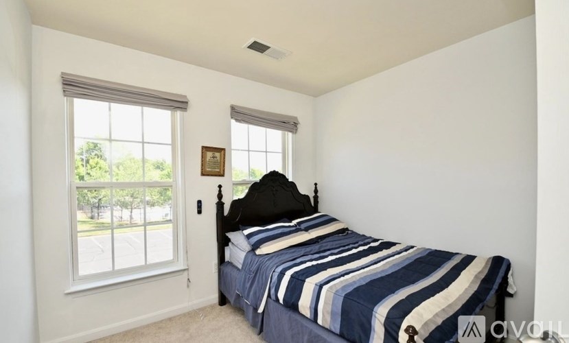 A bedroom with a bed, striped bedspread, and a window.