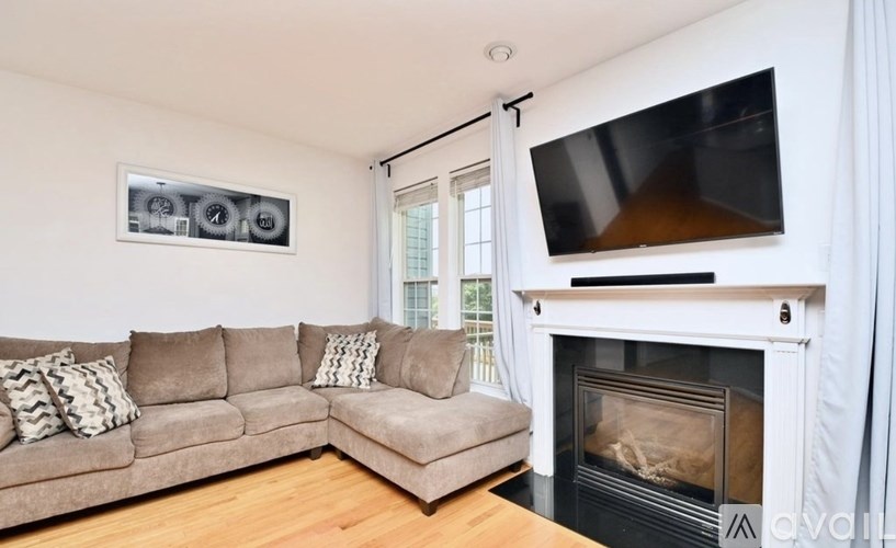 A living room with a couch, a fireplace, and a television mounted above it.