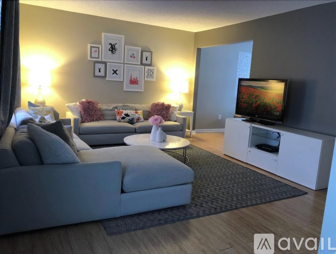 A living room with a grey couch, a white coffee table, and a television on a white cabinet.