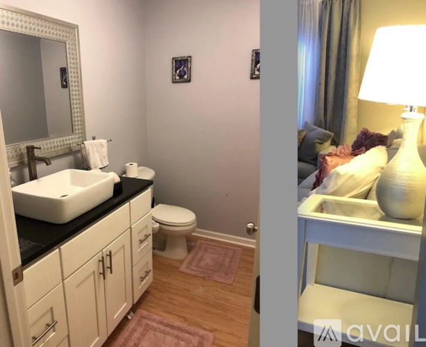 A bathroom with a sink, toilet, and a bedroom with a bed and lamp.