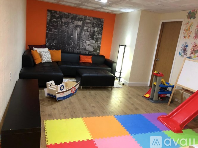 A living room with a black couch and a colorful rug.
