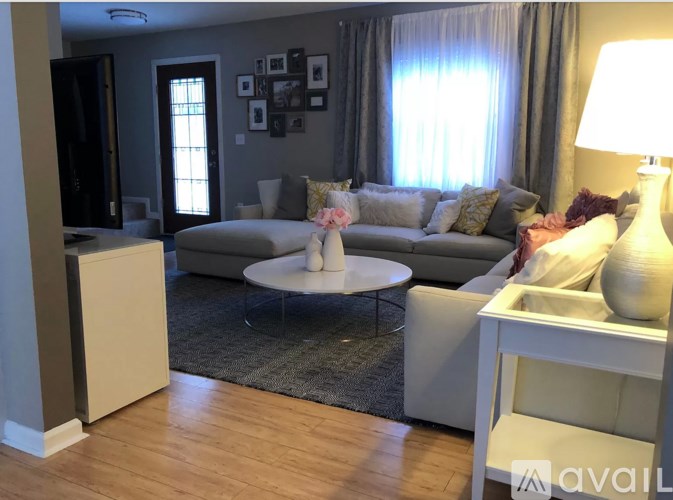 A living room with a grey couch, a white coffee table, and a white side table with a lamp.