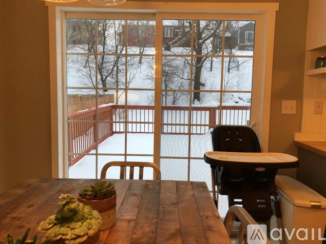 A table with a plant on it in front of a window with a view of a snowy landscape.